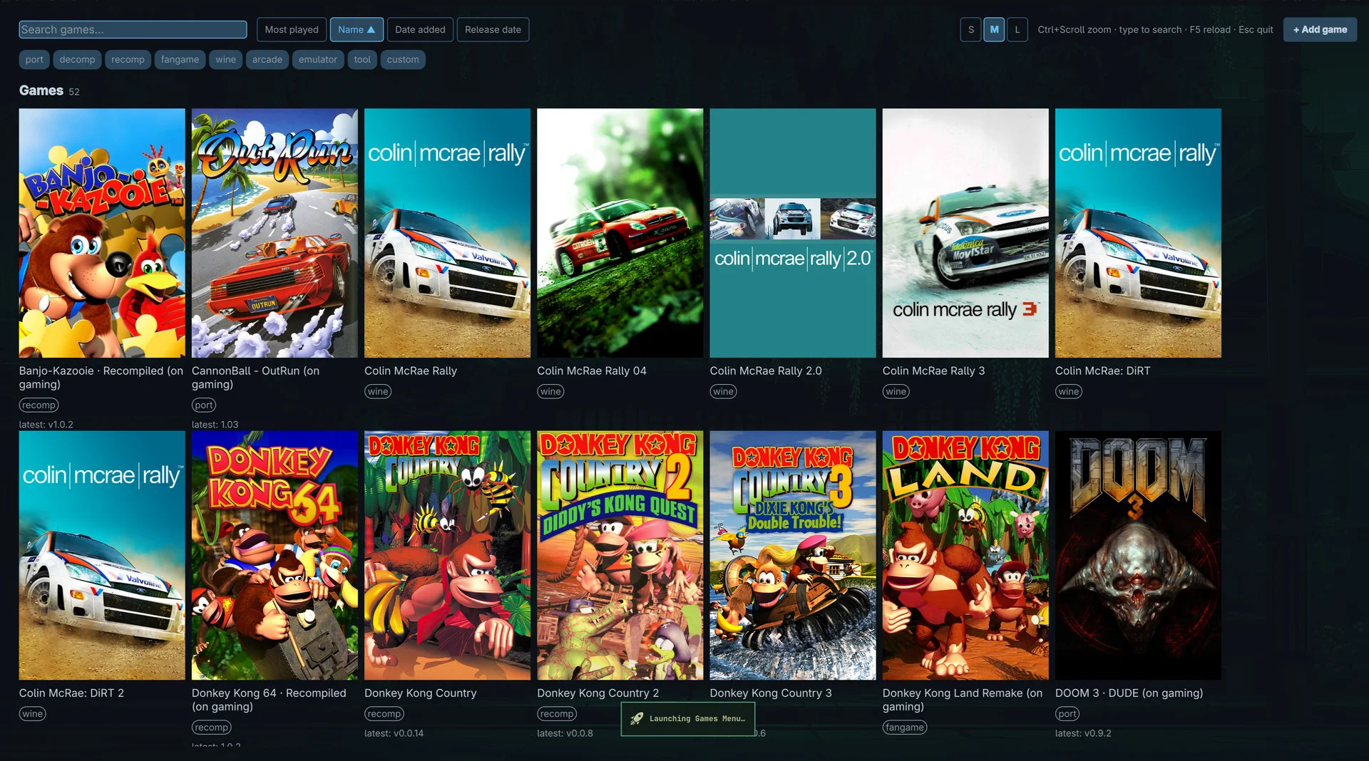 My games launcher on Omarchy: a fullscreen grid of 52 game covers including Banjo-Kazooie Recompiled, OutRun, the Colin McRae Rally series, Donkey Kong Country and DOOM 3, with category chips and sort buttons on top.
